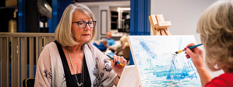 Passengers painting during an art class in the Craft Room on Spirit of Adventure